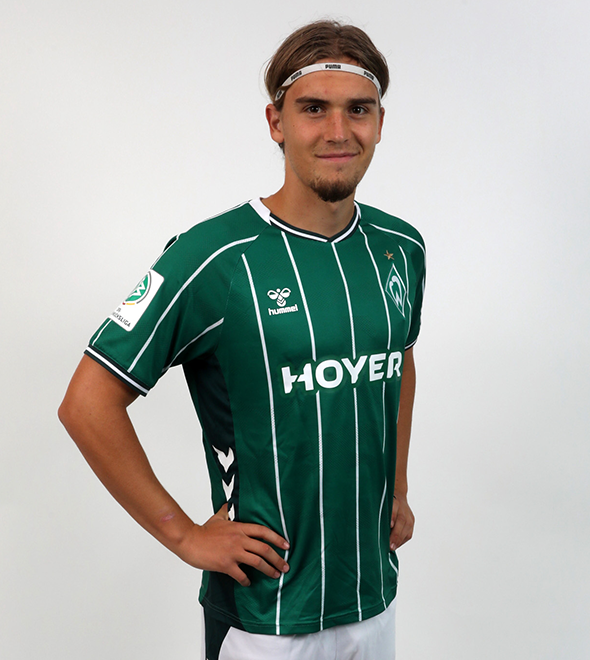 Portrait von Noah Weißbach. Er stemmt die Hände in die Hüften.