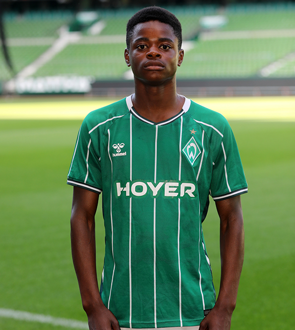 Portrait von Jeremiah Omoike. Er stemmt die Hände in die Hüften.