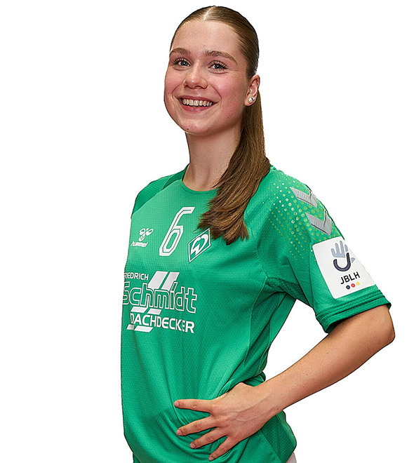 Eine junge Frau im grünen Sport-Shirt mit der Nummer 6 drauf, sie stemmt die Arme in die Hüften und lächelt.