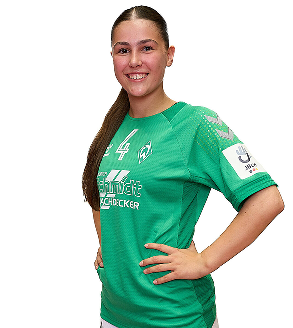 Eine junge Frau im grünen Sport-Shirt mit der Nummer 4 drauf, sie stemmt die Arme in die Hüften und lächelt.