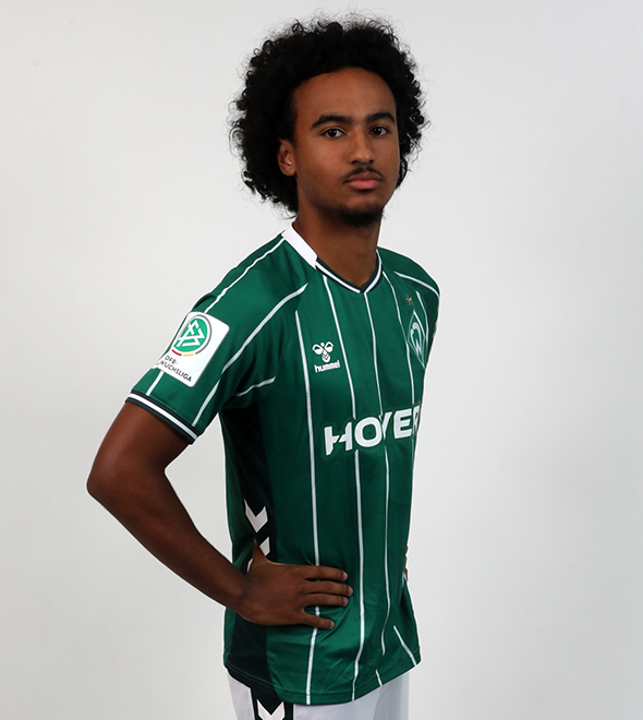 Portrait von Mario Mbassi. Er stemmt die Hände in die Hüften.