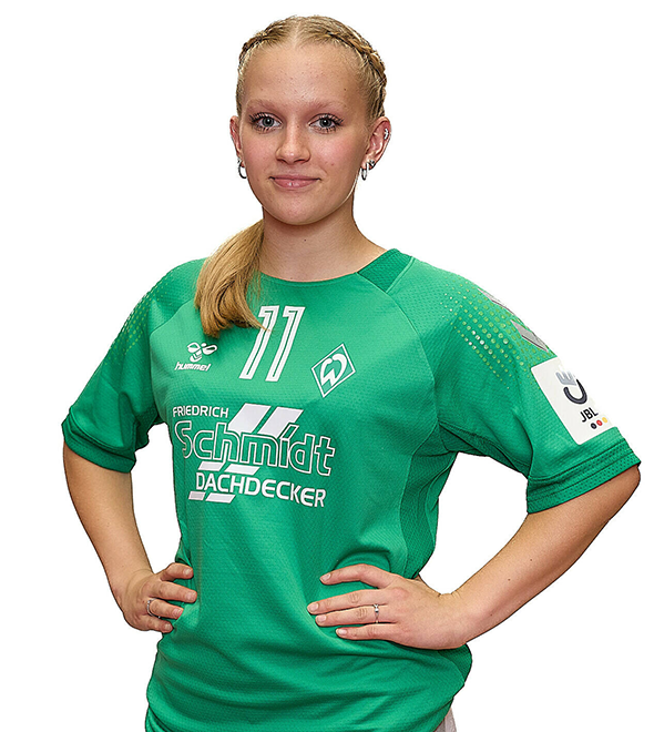 Eine junge Frau im grünen Sport-Shirt mit der Nummer 11 drauf, sie stemmt die Arme in die Hüften und lächelt.