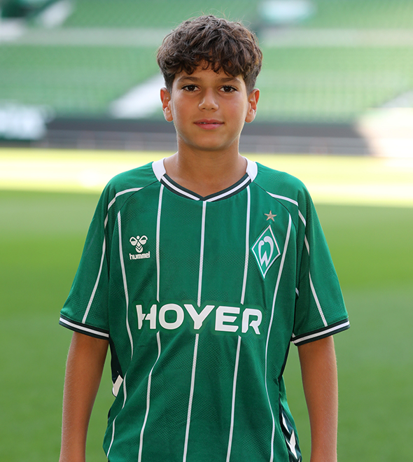 Portrait von Yassin Haddou. Er stemmt die Hände in die Hüften.