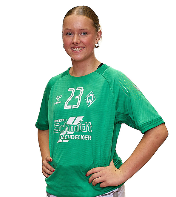 Eine junge Frau im grünen Sport-Shirt mit der Nummer 23 drauf, sie stemmt die Arme in die Hüften und lächelt.