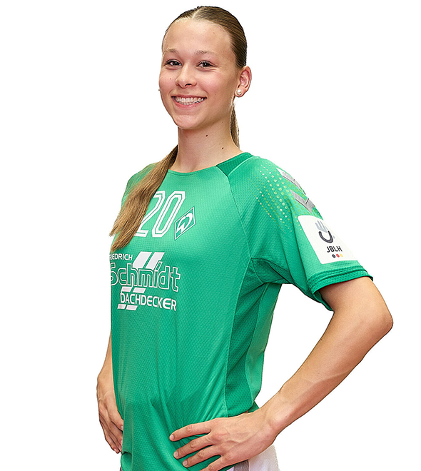 Eine junge Frau im grünen Sport-Shirt mit der Nummer 20 drauf, sie stemmt die Arme in die Hüften und lächelt.