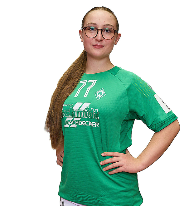 Eine junge Frau im grünen Sport-Shirt mit der Nummer 77 drauf, sie stemmt die Arme in die Hüften und lächelt.