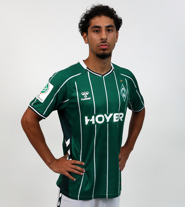 Portrait von Boran-Firat Coskun. Er stemmt die Hände in die Hüften.