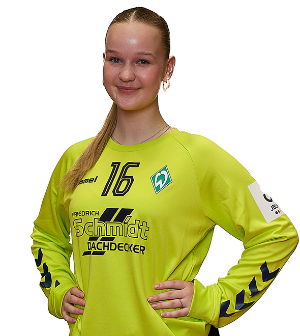 Eine junge Frau im gelben Sport-Shirt mit der Nummer 16 drauf, sie stemmt die Arme in die Hüften und lächelt.