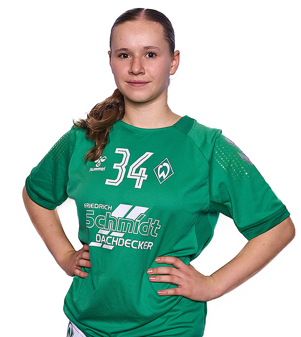 Eine junge Frau im grünen Sport-Shirt mit der Nummer 34 drauf, sie stemmt die Arme in die Hüften und lächelt.