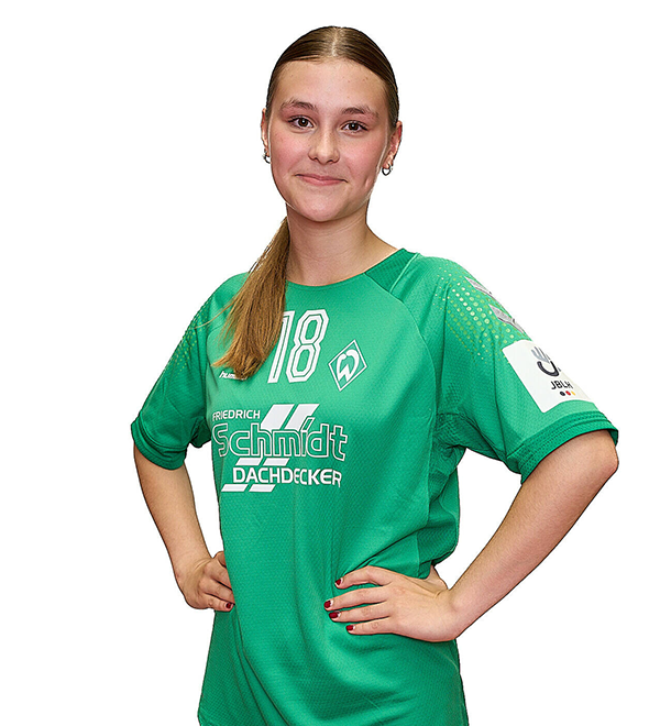 Eine junge Frau im grünen Sport-Shirt mit der Nummer 18 drauf, sie stemmt die Arme in die Hüften und lächelt.