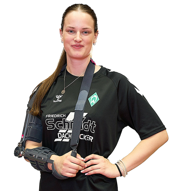 Eine Frau im schwarzen Sport-Shirt, sie stemmt die Arme in die Hüften und lächelt.