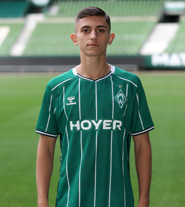 Portrait von Adis Mehic. Er stemmt die Hände in die Hüften.