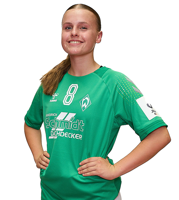 Eine junge Frau im grünen Sport-Shirt mit der Nummer 8 drauf, sie stemmt die Arme in die Hüften und lächelt.