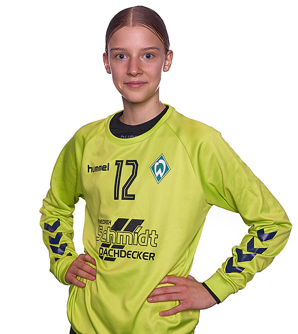 Eine junge Frau im gelben Sport-Shirt mit der Nummer 12 drauf, sie stemmt die Arme in die Hüften und lächelt.
