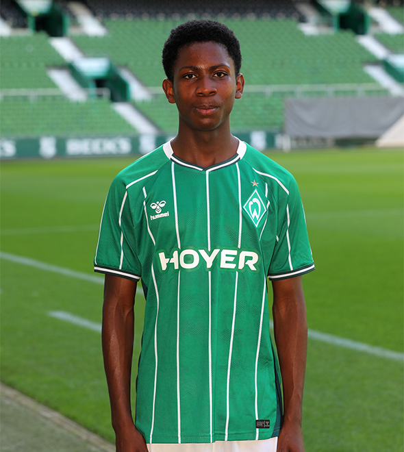 Portrait von Roland Agyemang. Er stemmt die Hände in die Hüften.