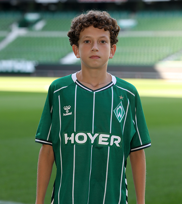 Portrait von Kerem Bozkurt. Er stemmt die Hände in die Hüften.