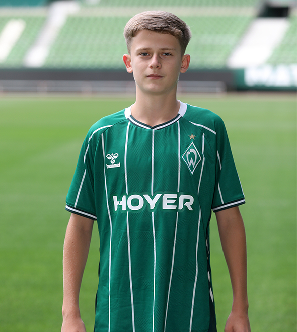 Portrait von Noah Mazur. Er stemmt die Hände in die Hüften.