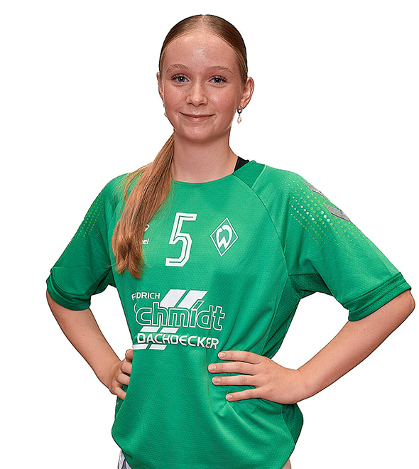 Eine junge Frau im grünen Sport-Shirt mit der Nummer 5 drauf, sie stemmt die Arme in die Hüften und lächelt.