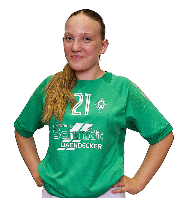 Eine junge Frau im grünen Sport-Shirt mit der Nummer 21 drauf, sie stemmt die Arme in die Hüften und lächelt.