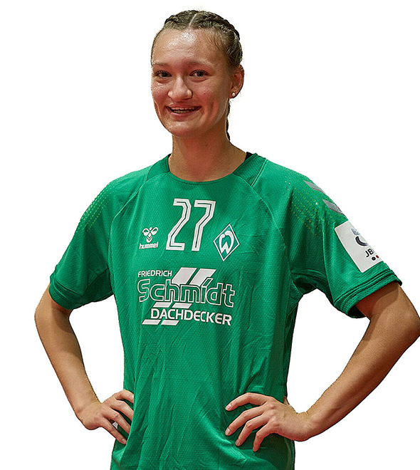 Eine junge Frau im grünen Sport-Shirt mit der Nummer 27 drauf, sie stemmt die Arme in die Hüften und lächelt.