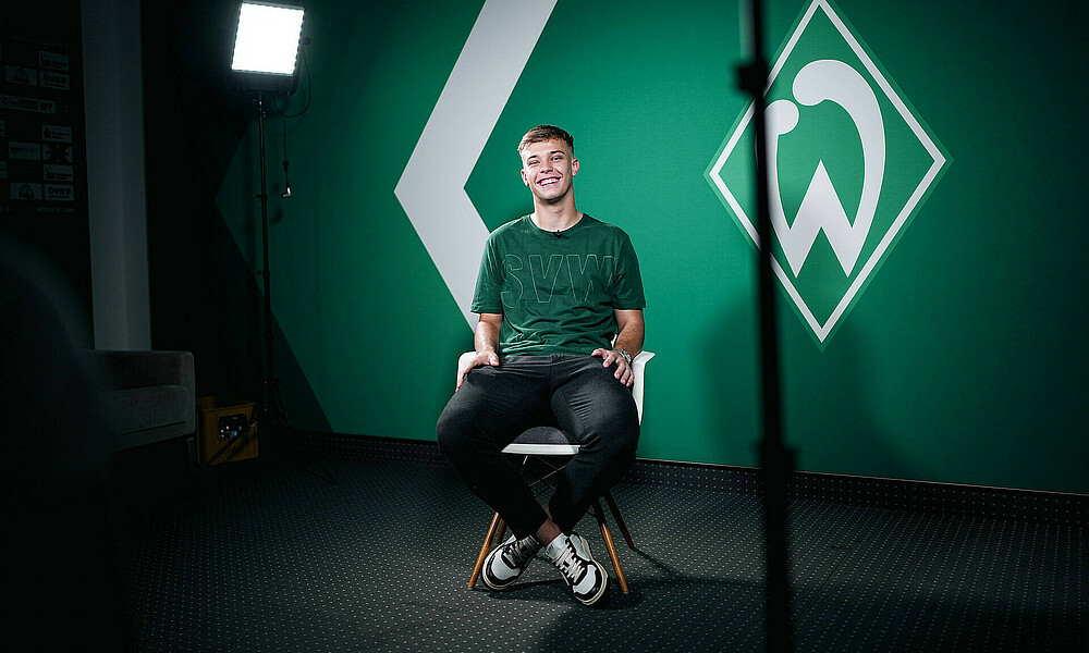 null Keke Topp sitzt auf einem Stuhl vor einer grünen Wand. Rechts hinten steht ein Scheinwerfer.