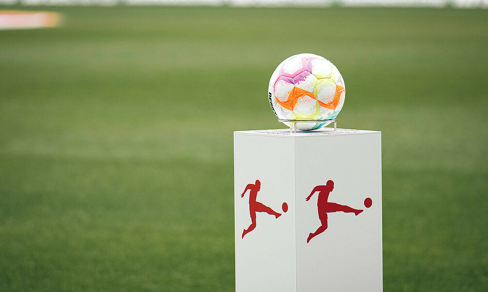 Der Spielball liegt auf einem Podest vor dem Spiel. Im Hintergrund der Rasen. 