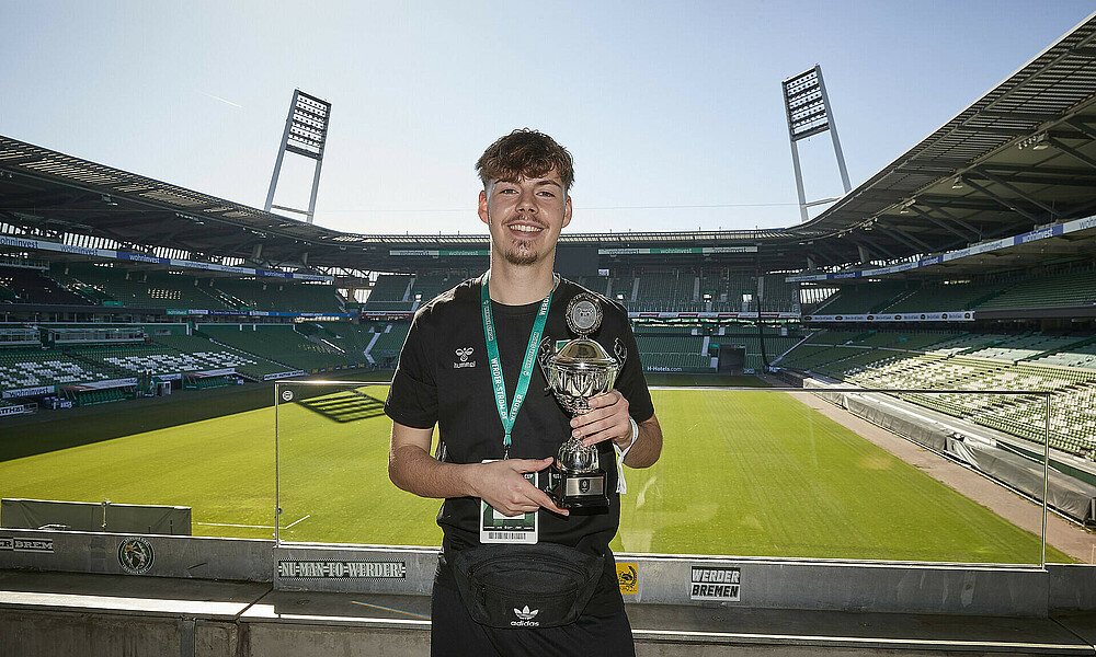 Der strahlende Sieger mit einem Pokal in der Hand. 