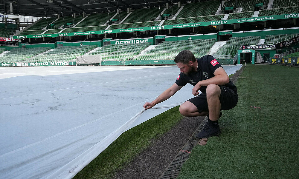 Tim Engelke schaut sich den Rasen im wohninvest WESERSTADION an. 