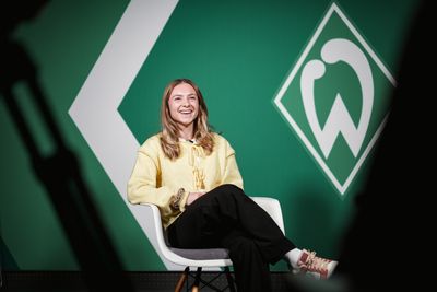 Michelle Weiß sitzt im Interview und lacht. Hinter ihr ist die Werder-Raute an der Wand zu sehen.