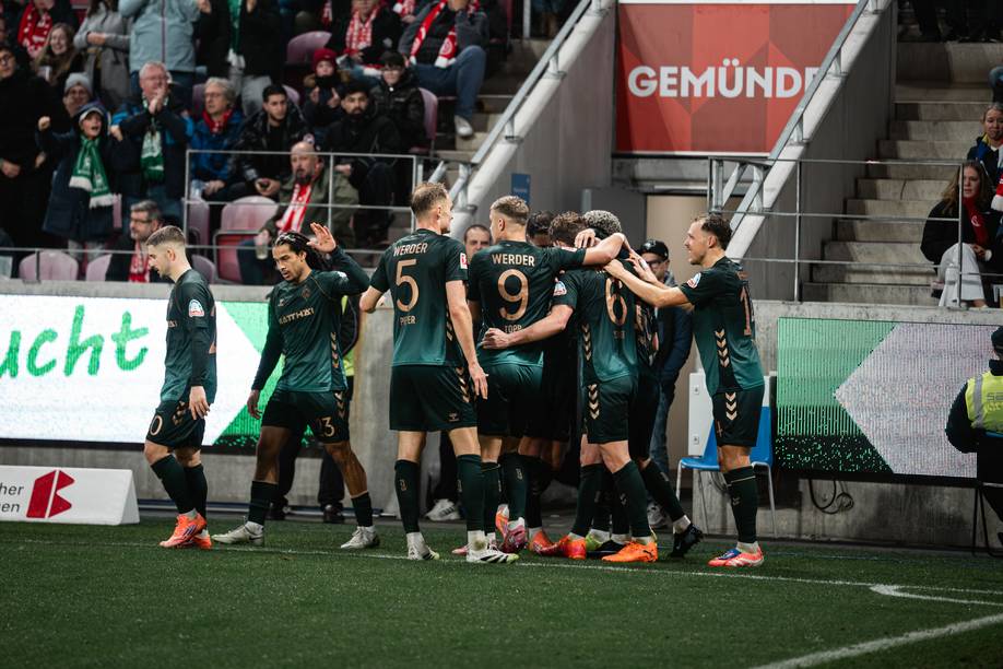 Die Werder-Spieler in dunkelgrünen Trikots mit bronzener Schrift jubeln gemeinsam.