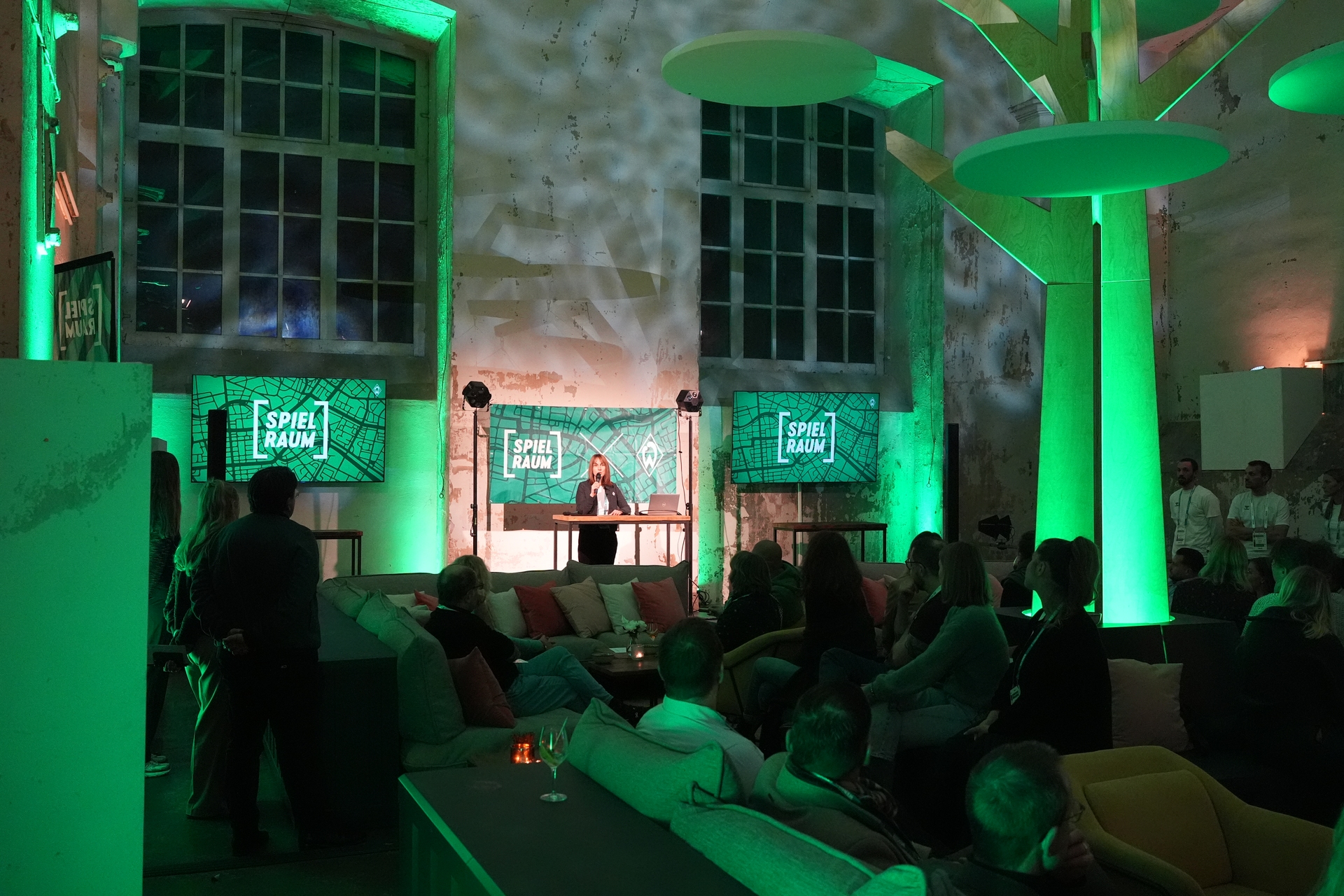 Anne-Kathrin Laufmann steht an einem Tisch und hält einen Vortrag.