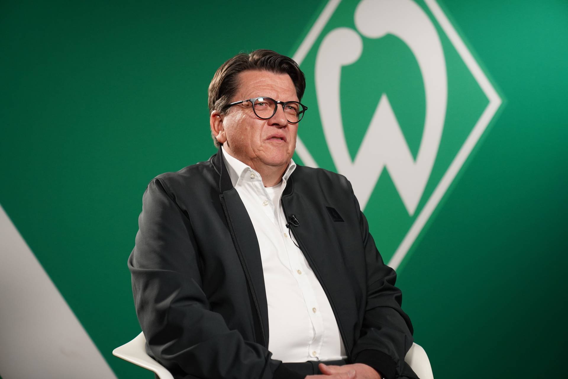 Hubertus Hess-Grunewald im TV-Studio vor einer Werder-Raute.