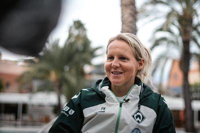 Fritzy Kromp lächelnd während des Interviews mit Palmen im Hintergrund.