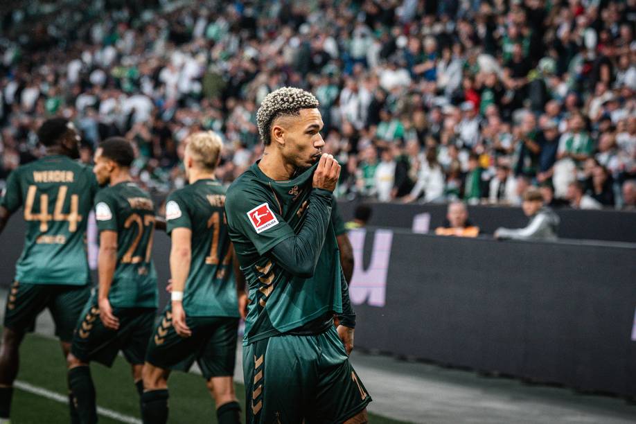 Justin Njinmah jubelt vor der Gästekurve und küsst sein Wappen.