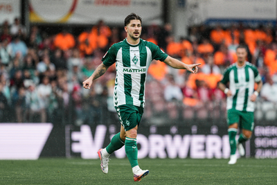 Romano Schmid zeigt nach vorne, während er im grün-weißen Home-Trikot beim Testspiel gegen Energie Cottbus auf dem Platz steht.
