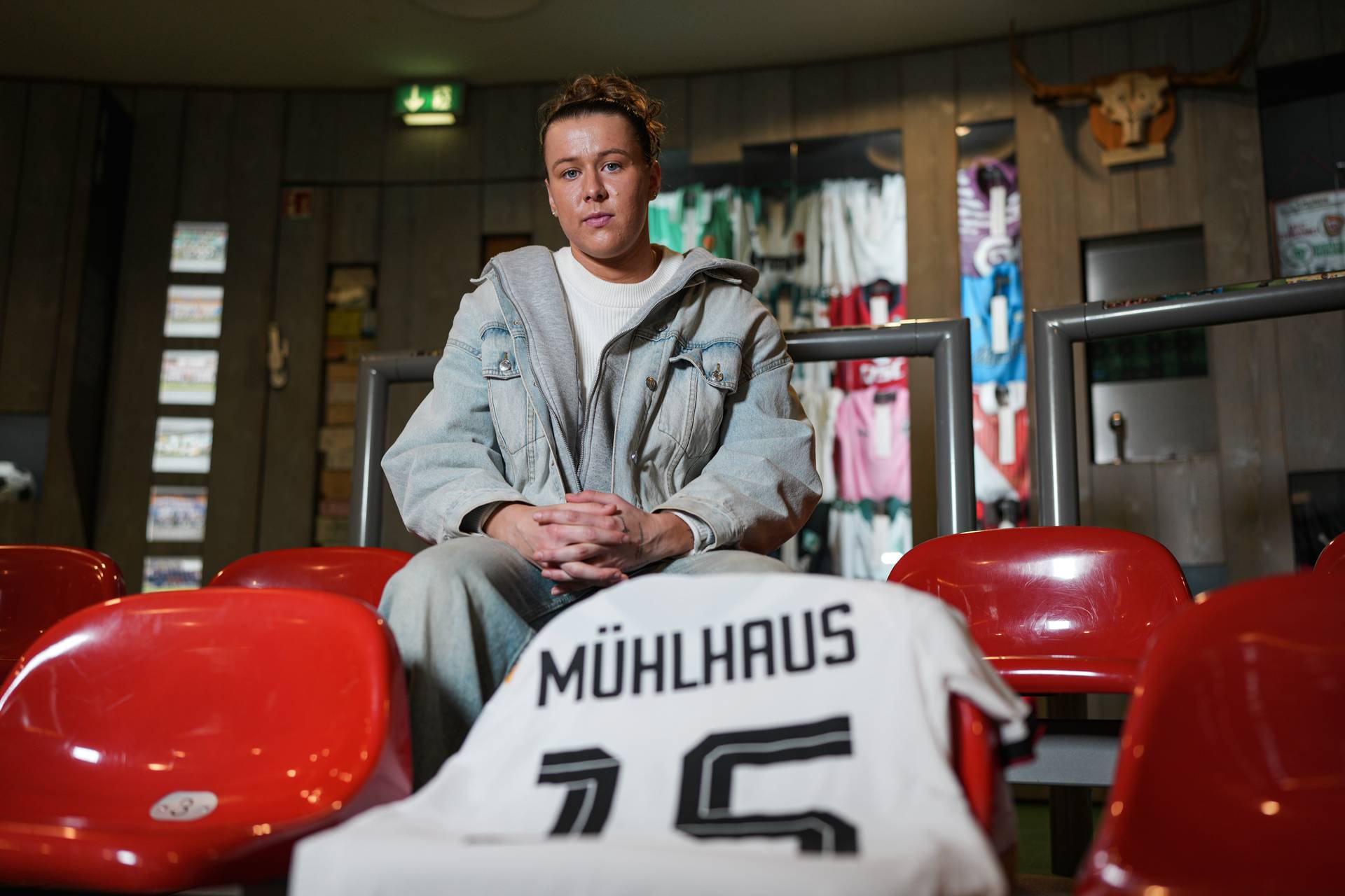 Larissa Mühlhaus sitzt im Werder-Wuseum, vor ihr liegt das Trikot der Nationalmannschaft mit ihrem Namensflock.