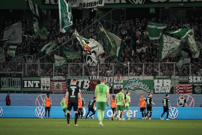 Der Bremer-Auswärtsblock im Stadion des VfL Wolfsburg mit schwenkenden Fahnen.