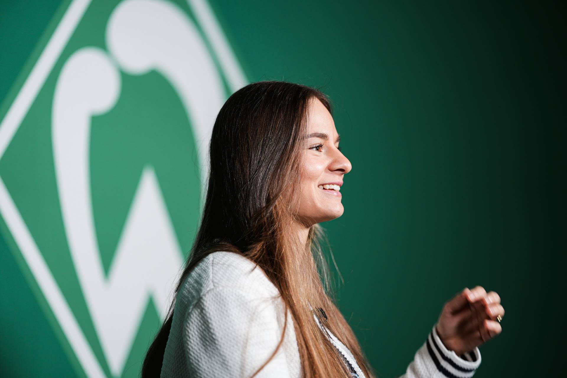 Tuana Mahmoud lacht beim Interview, im Hintergrund ist die Werder-Raute zu sehen.