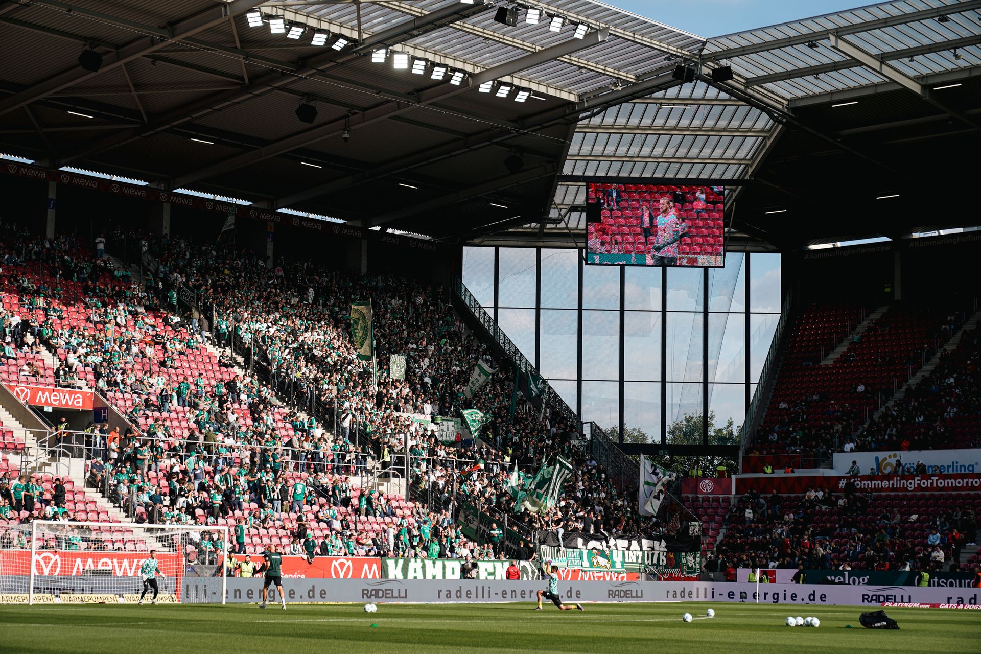 Ein Stadion voller Werder-Fans in grüner Kleidung, mit Transparenten und Fahnen, während eines Fußballspiels.