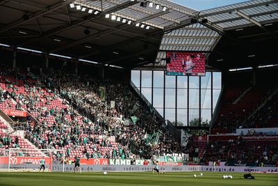 Ein Stadion voller Werder-Fans in grüner Kleidung, mit Transparenten und Fahnen, während eines Fußballspiels.