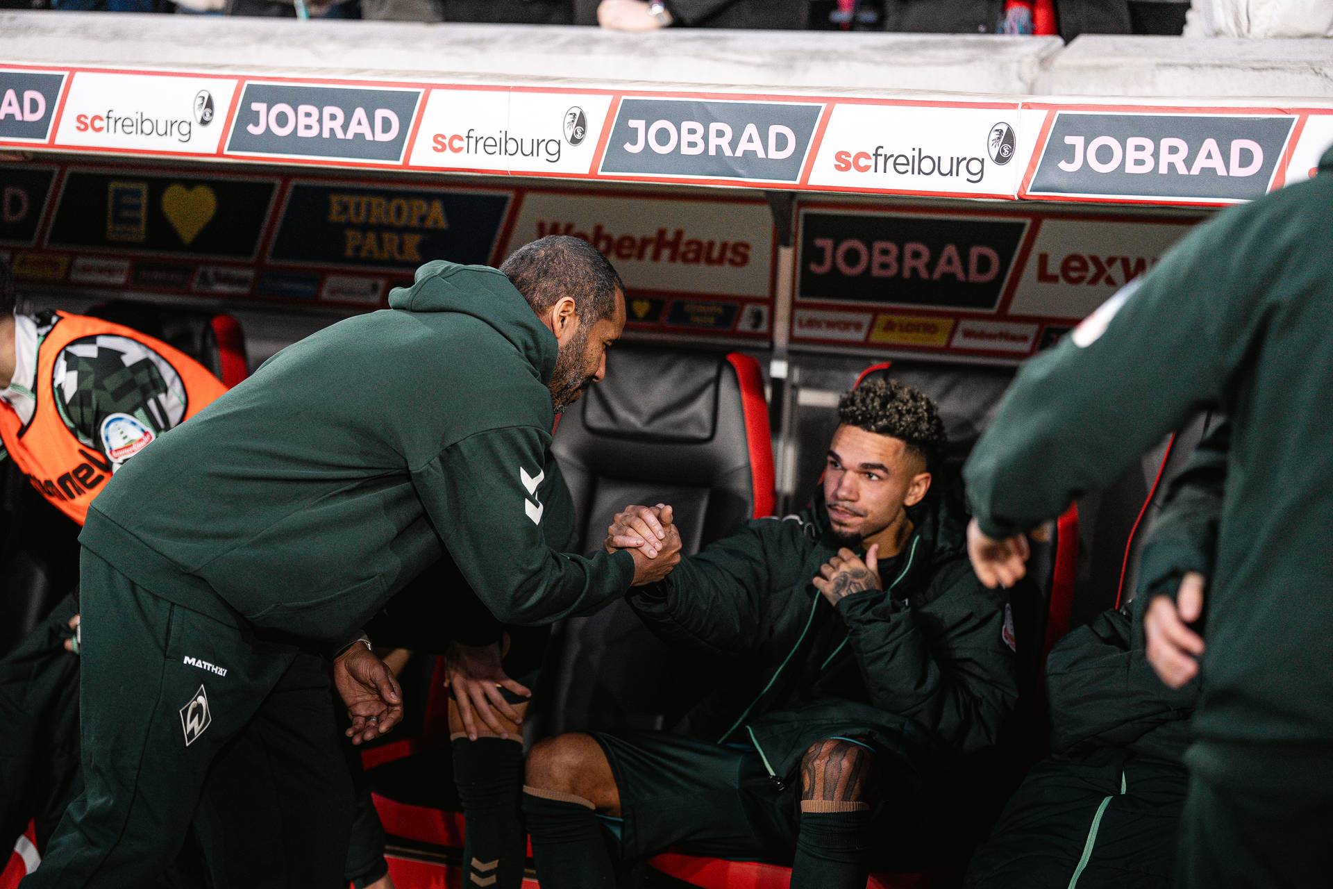 Daniel Thioune klatscht mit Justin Njinmah ab, der enttäuscht auf der Bank sitzt.