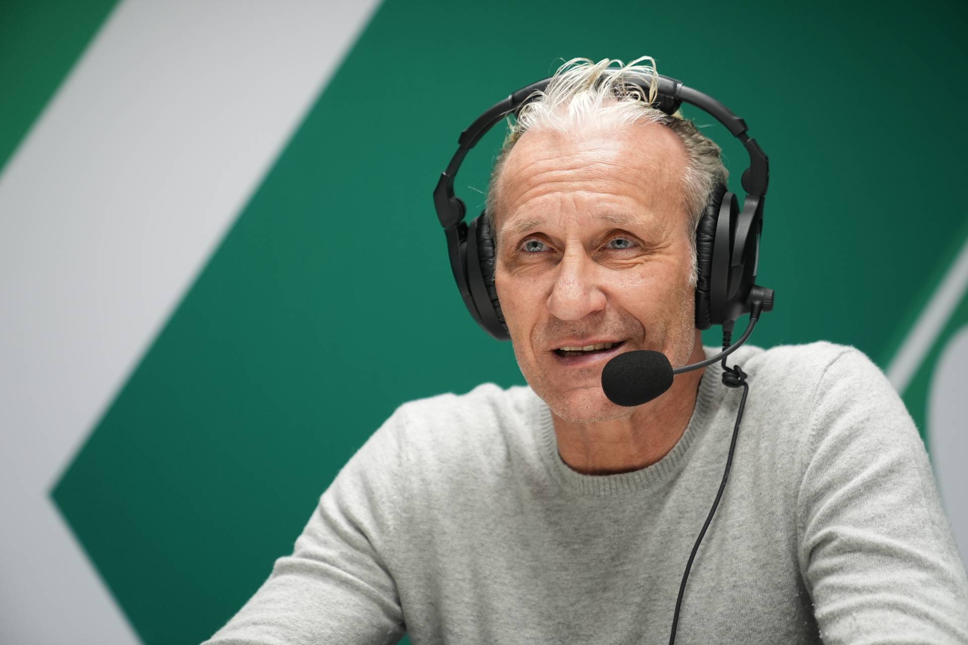 Thomas Wolter mit Kopfhörern vor Werder-Raute.