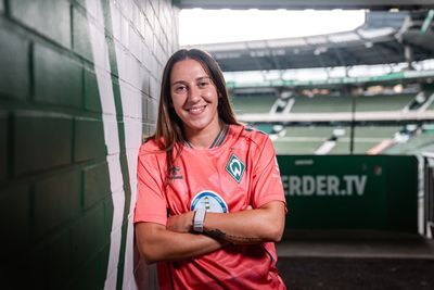 Wiktoria Zieniewicz lehnt an einer grünen Mauer und trägt das Trikot "third".