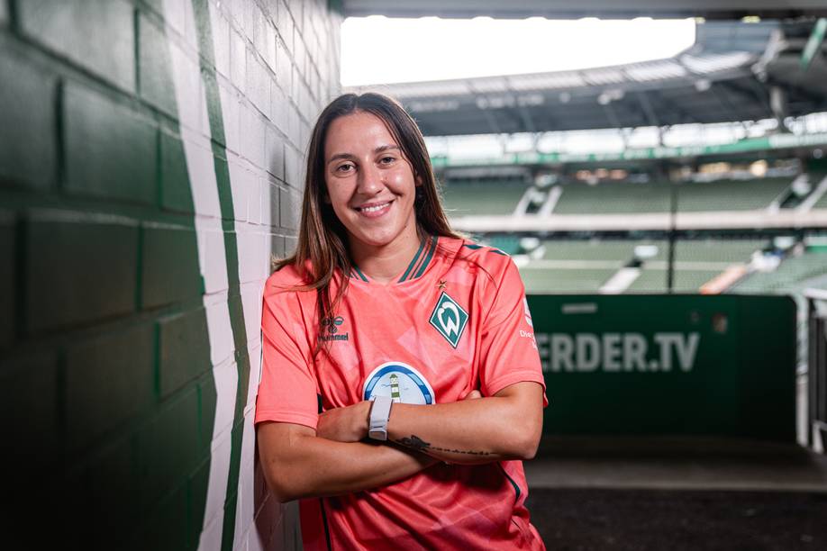 Wiktoria Zieniewicz lehnt an einer grünen Mauer und trägt das Trikot "third".