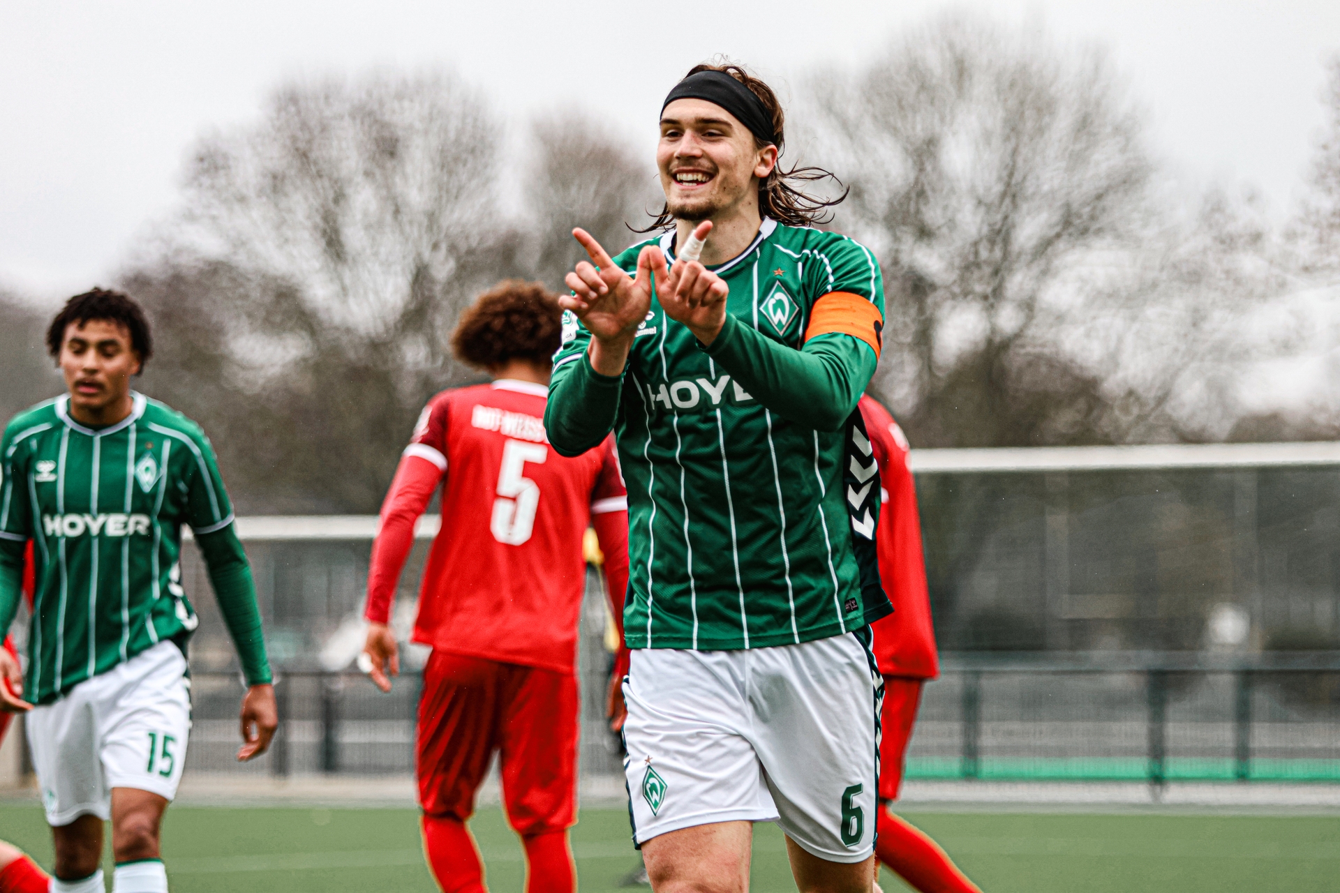 Noah Weißhaupt zeigt mit seinen Fingern ein W in die Kamera.