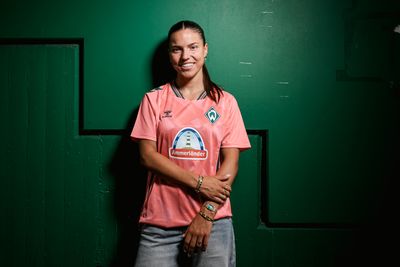 Luna Vanzeir steht im neuen Trikot third vor einer grünen Wand und lächelt.