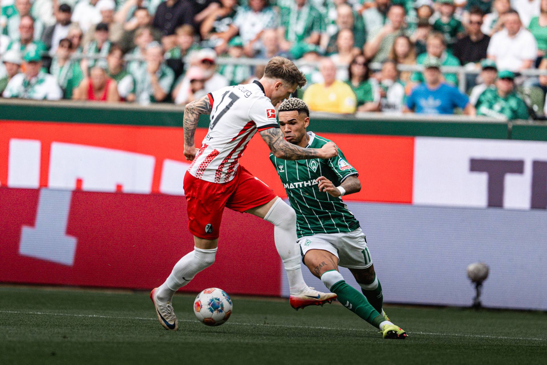 Justin Njinmah im Zweikampf mit Freiburgs Kübler, er richtet die Augen auf den Ball.