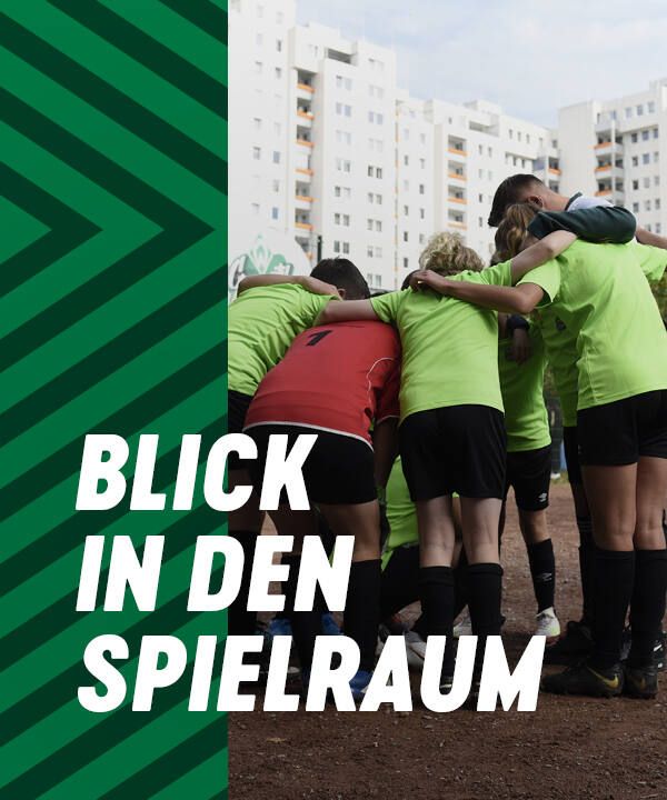 Eine Fußballmannschaft in grünen Trikots steht auf einem Feld mit Sandboden, im Hintergrund sind hohe Gebäude zu sehen. Der Text lautet „Blick in den Spielraum“.