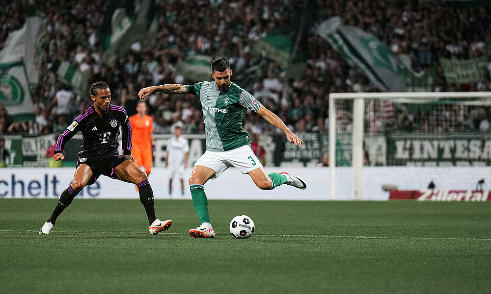 Tony Jung spielt einen Ball, neben ihm steht Sané.