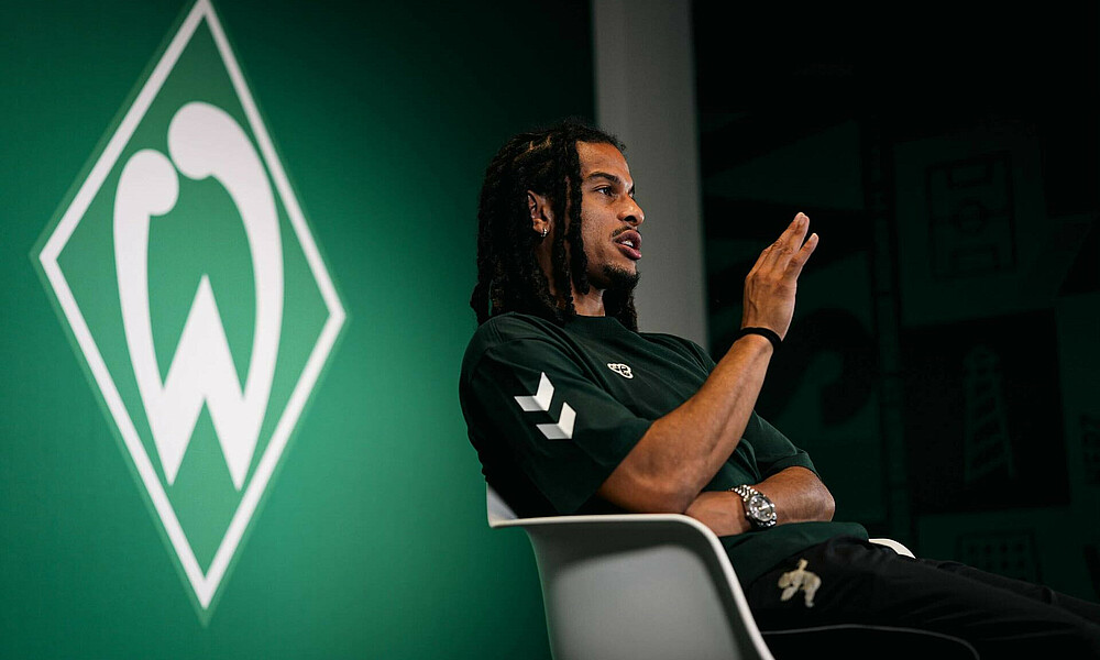 null Isaac Schmidt im Interview vor einer Werder-Raute.